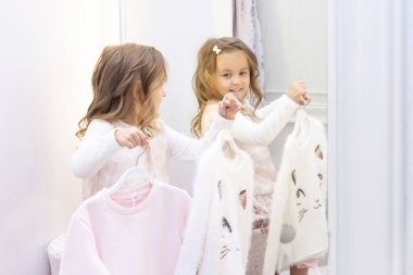 Alışveriş. Indirimler. küçük kız alışverişkolik. kız butik uygun odasında hafifçe pembe güzel bir elbise çalışıyor. Alışveriş merkezi, alışveriş. Duyguları