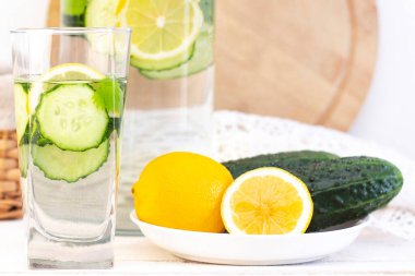 Sağlık hizmeti, fitness, sağlıklı beslenme konsepti. Taze soğuk limon salatalığı suyu, kokteyl, detoks içeceği, bardakta limonata ve bardakta. Bir tabakta salatalık ve limon