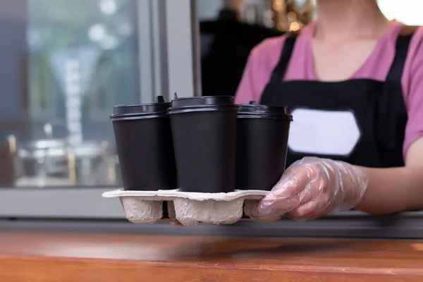 外卖咖啡 穿着围裙的巴里斯塔手里拿着纸杯里的热咖啡 咖啡店接咖啡 — 图库照片