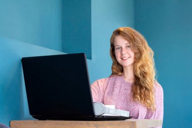 Kız dizüstü bilgisayar için çalışıyor. Uzaktan kumanda çevrimiçi. Bir kafede kahve içen bir kız.