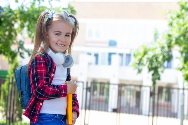 Gelukkig Schoolmeisje Met Een Leerboek Haar Handen Met Hoofdtelefoon Nek — Stockfoto