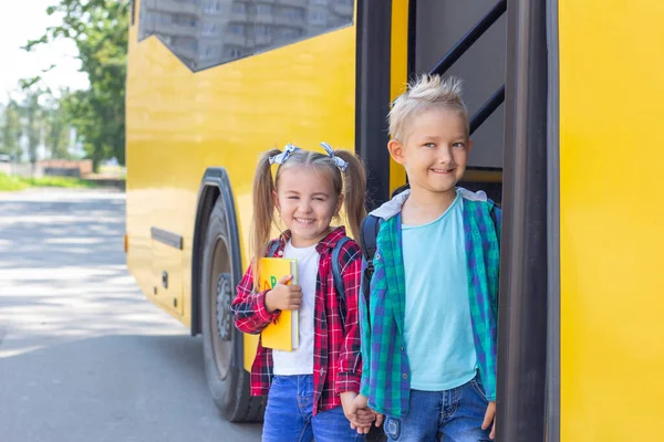 happy schoolchildren with backpacks get off the school bus.