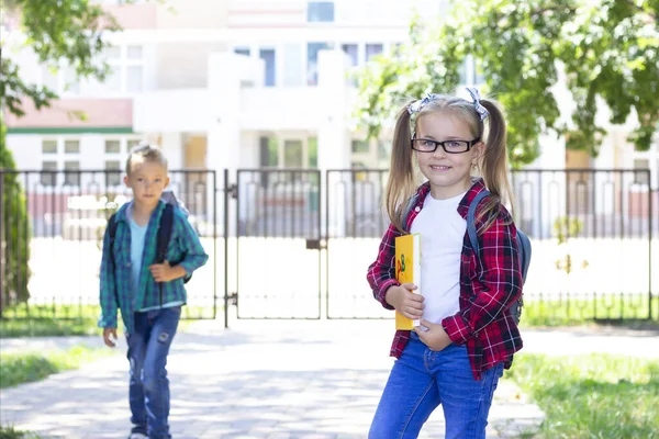 バックパックを持った子供たちがお出迎え 男子学生と女子学生が笑顔で — ストック写真