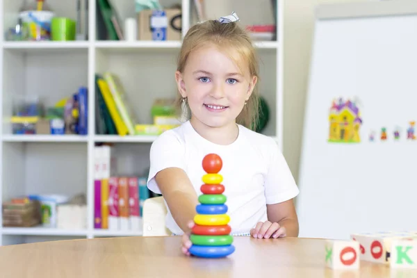 developmental and speech therapy classes with a child-girl. Speech therapy exercises and games with a colored pyramid