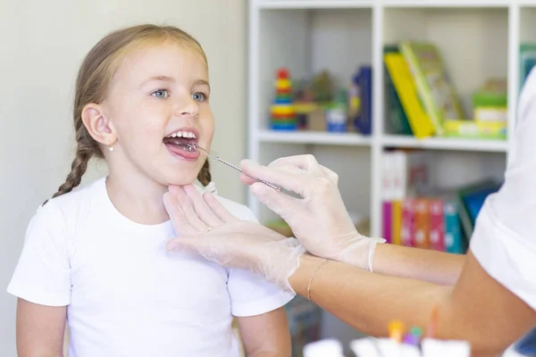 Speech therapy massage of the girl\'s tongue. a speech therapist makes a tongue massage to a child with a staging probe.