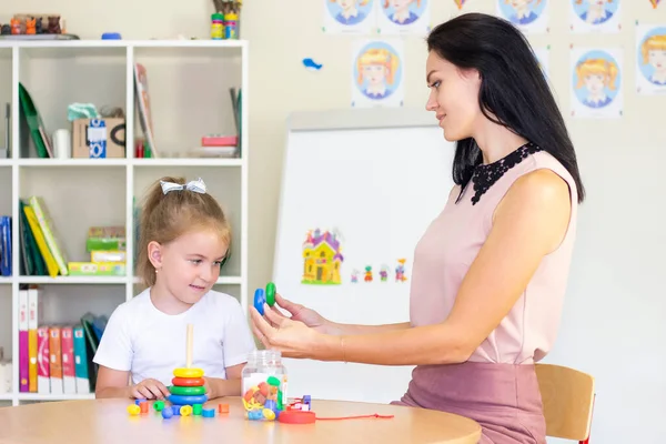 speech therapist teaches a girl. collect childrens pyramid, child development, fine motor skills