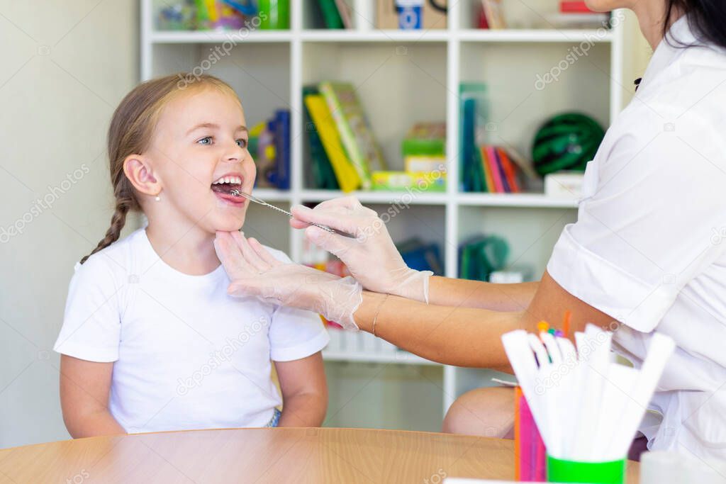 Speech therapy massage of the girl's tongue. a speech therapist makes a tongue massage to a child with a staging probe.