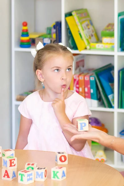 Speech therapist teaches the girl to say the letter