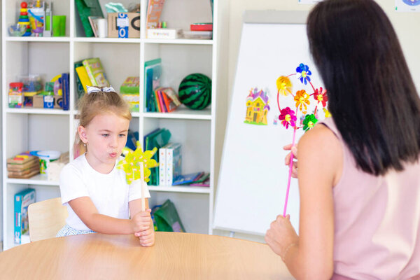 developmental and speech therapy classes with a child-girl. Speech therapy and spinning games. girl blowing