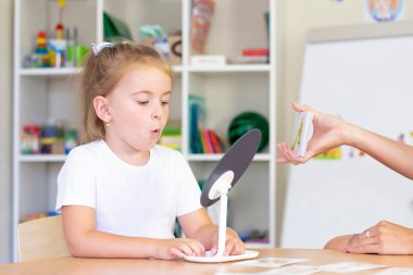 developmental and speech therapy classes with a child-girl. Speech therapy exercises and games with a mirror and cards clipart