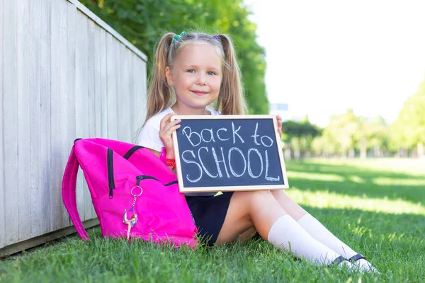 Scolaretta Siede Sull Erba Zaino Della Scuola Tiene Segno Tra — Foto Stock