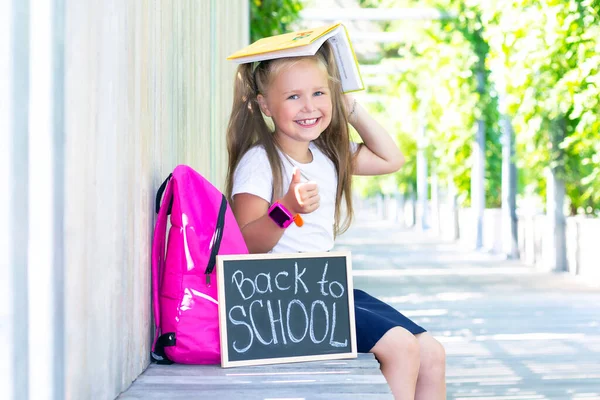 Schoolmeisje Zit Met Een Rugzak Een Bord Met Inscriptie Terug — Stockfoto