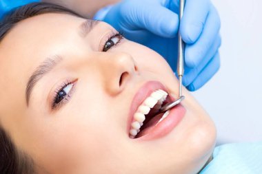 Güzel gülüşü olan genç bir bayan hasta dişçi kliniğinde diş muayenesi yapıyor. Sağlıklı dişler ve ilaçlar, stomatoloji konsepti