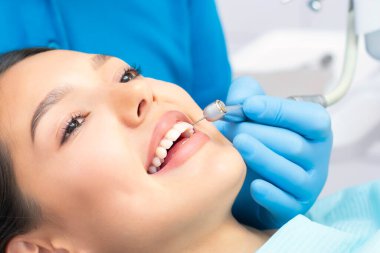 Güzel gülüşü olan genç bir bayan hasta dişçi kliniğinde diş muayenesi yapıyor. Sağlıklı dişler ve ilaçlar, stomatoloji konsepti