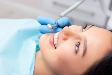Güzel gülüşü olan genç bir bayan hasta dişçi kliniğinde diş muayenesi yapıyor. Sağlıklı dişler ve ilaçlar, stomatoloji konsepti