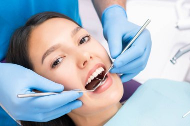 Diş sağlığı konsepti. Diş kliniğinde tedavi gören gülümseyen bir kadının kesik fotoğrafı.