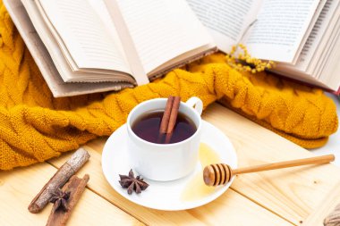 Ahşap sonbahar arka planında sıcak bir eşarpla kaplanmış aromatik sıcak tarçın çayı. Ballı balım. rahatça kitap okuyabilirsiniz