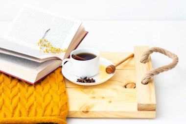 Ahşap sonbahar arka planında sıcak bir eşarpla kaplanmış aromatik sıcak tarçın çayı. Ballı balım. rahatça kitap okuyabilirsiniz