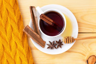 Ahşap sonbahar arka planında sıcak bir eşarpla kaplanmış aromatik sıcak tarçın çayı. Ballı şeker.