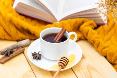 Ahşap sonbahar arka planında sıcak bir eşarpla kaplanmış aromatik sıcak tarçın çayı. Ballı balım. rahatça kitap okuyabilirsiniz