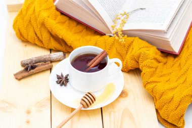 Ahşap sonbahar arka planında sıcak bir eşarpla kaplanmış aromatik sıcak tarçın çayı. Ballı balım. rahatça kitap okuyabilirsiniz