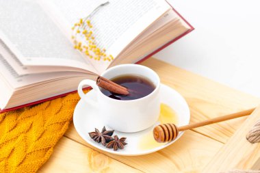 Ahşap sonbahar arka planında sıcak bir eşarpla kaplanmış aromatik sıcak tarçın çayı. Ballı balım. rahatça kitap okuyabilirsiniz