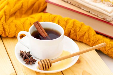 Ahşap sonbahar arka planında sıcak bir eşarpla kaplanmış aromatik sıcak tarçın çayı. Ballı balım. rahatça kitap okuyabilirsiniz