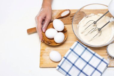 Ekmek ya da ev yapımı hamur işi yapmak. Malzemeler masanın üstünde. Kadın elleri hamuru karıştırmak için mikser tutuyor.