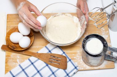 Ekmek ya da ev yapımı hamur işi yapmak. Malzemeler masanın üstünde. Yumurta tutan kadın elleri