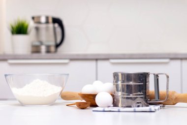 Ekmek ya da ev yapımı hamur işi yapmak. Malzemeler masanın üstünde. Parlak, modern bir mutfağın arka planında.