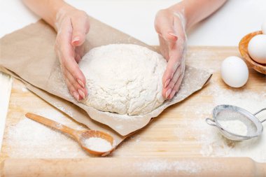 Ev yemeği konsepti. Kadın elleri un ahşap bir tahtanın üzerinde ev yapımı hamuru hazırlar. Yakın plan..