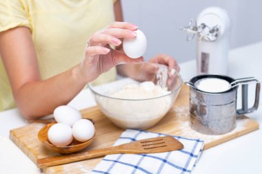 Ekmek ya da ev yapımı hamur işi yapmak. Malzemeler masanın üstünde. Yumurta tutan kadın elleri
