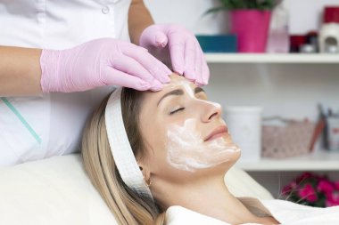 Kozmetoloji. Güzellik salonunda yüzü kapalı genç bir kadının yüz temizleme ameliyatı olurken yakın plan fotoğrafı..