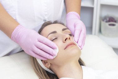 Kozmetoloji. Güzellik salonunda yüzü kapalı genç bir kadının yüz temizleme ameliyatı olurken yakın plan fotoğrafı..