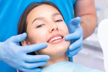 Diş hekimi ve hasta muayenehanesinde. Dişleri dişçiler tarafından incelenen bir kadın.