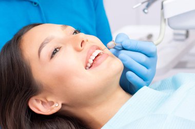 Diş hekimi ve hasta muayenehanesinde. Dişleri dişçiler tarafından incelenen bir kadın.