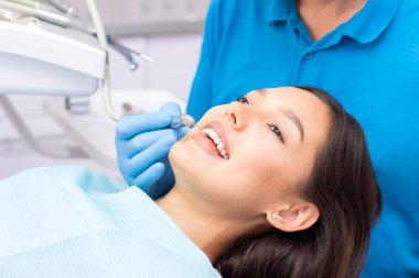 Diş hekimi ve hasta muayenehanesinde. Dişleri dişçiler tarafından incelenen bir kadın.