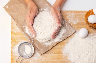 Ev yemeği konsepti. Kadın elleri un ahşap bir tahtanın üzerinde ev yapımı hamuru hazırlar. Yakın plan..