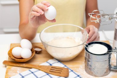 Ekmek ya da ev yapımı hamur işi yapmak. Malzemeler masanın üstünde. Yumurta tutan kadın elleri