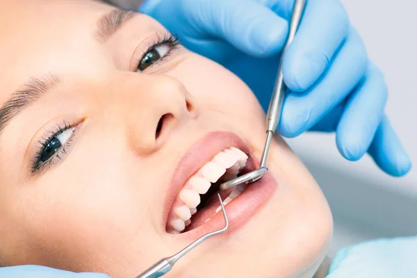 Erkek bir dişçiyle dişçi kliniğinde çekici bir genç kadın. Sağlıklı diş konsepti.