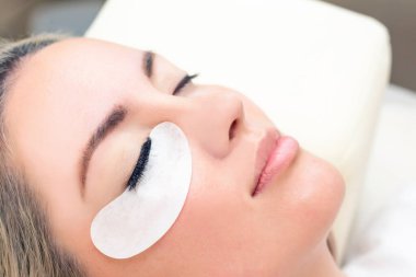 Kirpik uzatma prosedürü. Uzun kirpikli kadın gözü. Kapat.