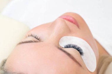 Kirpik uzatma prosedürü. Uzun kirpikli kadın gözü. Kapat.