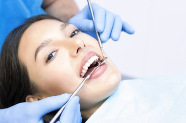 Diş hekimi ve hasta muayenehanesinde. Dişleri dişçiler tarafından incelenen bir kadın.