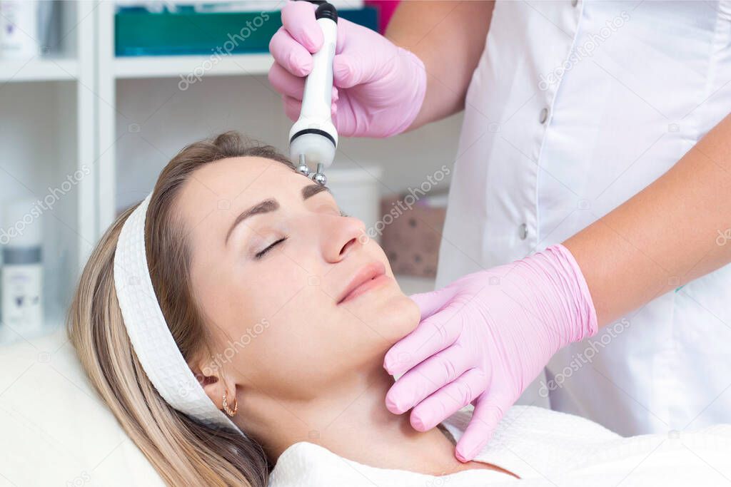 Hardware cosmetology. Close up picture of lovely young woman with closed eyes receiving rf lifting procedure in beauty salon.