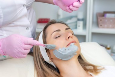 Genç kadın gri aljinat bir maske takıyor. Kozmetik prosedürleri