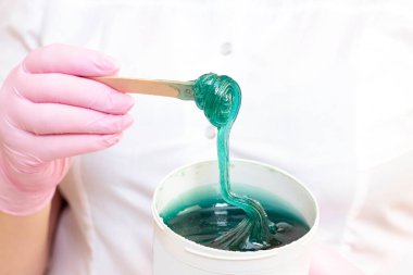 Deri epilasyonu için sıvı şeker. Yakın çekim. Kozmetik uzmanı tüy dökülmesi için bir kavanoz şeker tutuyordu..