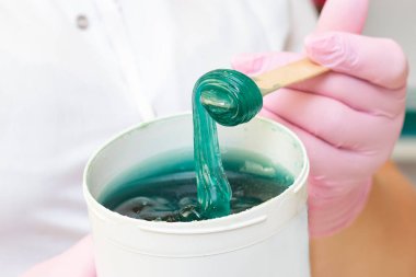 Deri epilasyonu için sıvı şeker. Yakın çekim. Kozmetik uzmanı tüy dökülmesi için bir kavanoz şeker tutuyordu..