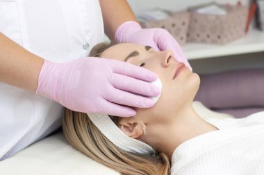 Kozmetoloji. Güzellik salonunda yüzü kapalı genç bir kadının yüz temizleme ameliyatı olurken yakın plan fotoğrafı..