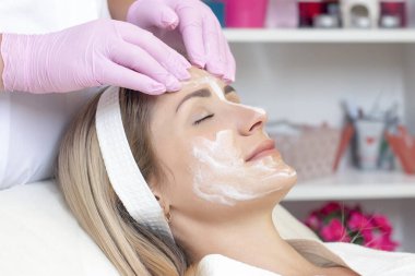 Kozmetoloji. Güzellik salonunda yüzü kapalı genç bir kadının yüz temizleme ameliyatı olurken yakın plan fotoğrafı..
