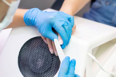 Manikürcü tırnak ve deri yüzeyini cilalar. Tırnak jölesi sürmeden önce.